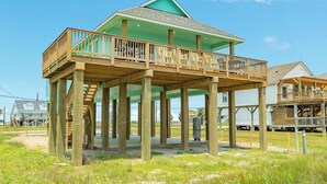 A wooden structure with a green roof and a balcony, supported by wooden pillars.