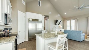 A spacious kitchen with a central island, white cabinetry, and a stainless steel refrigerator.