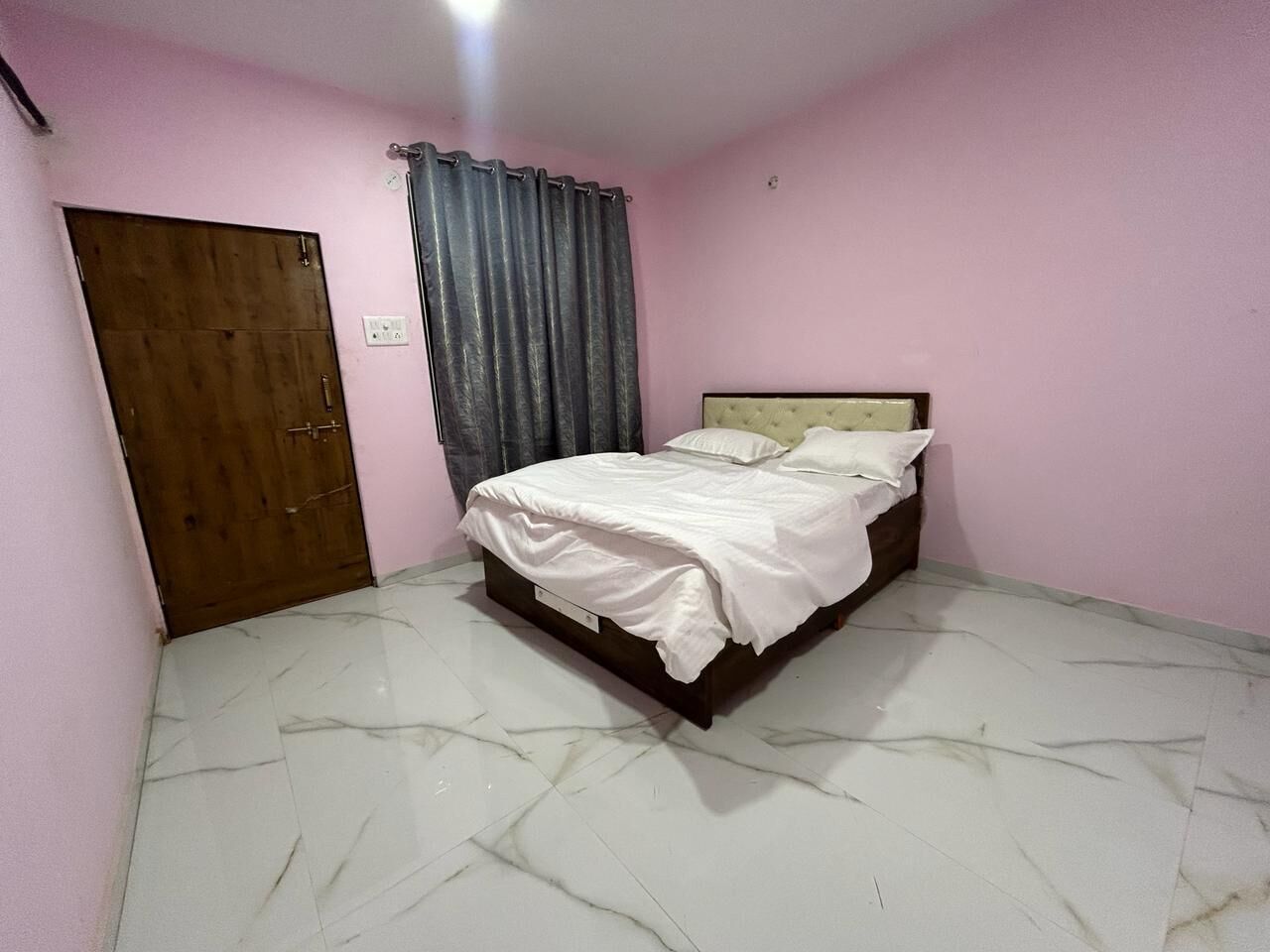 A bedroom with a bed, a wooden door, and a curtain.