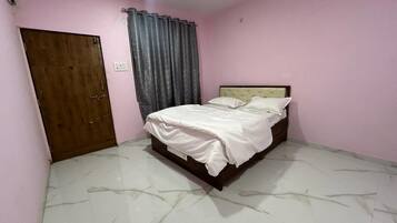 A bedroom with a bed, a wooden door, and a curtain.