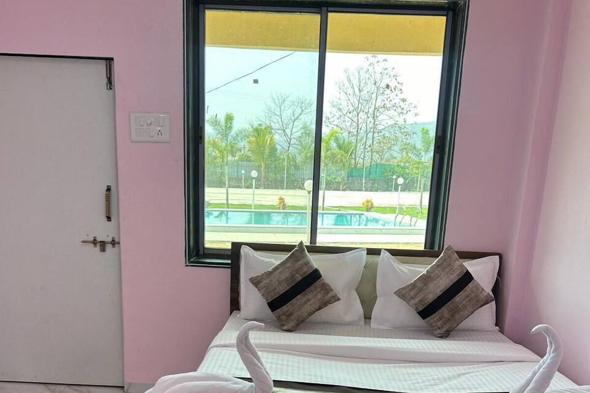 A bedroom with a bed, pillows, a window, and a door.