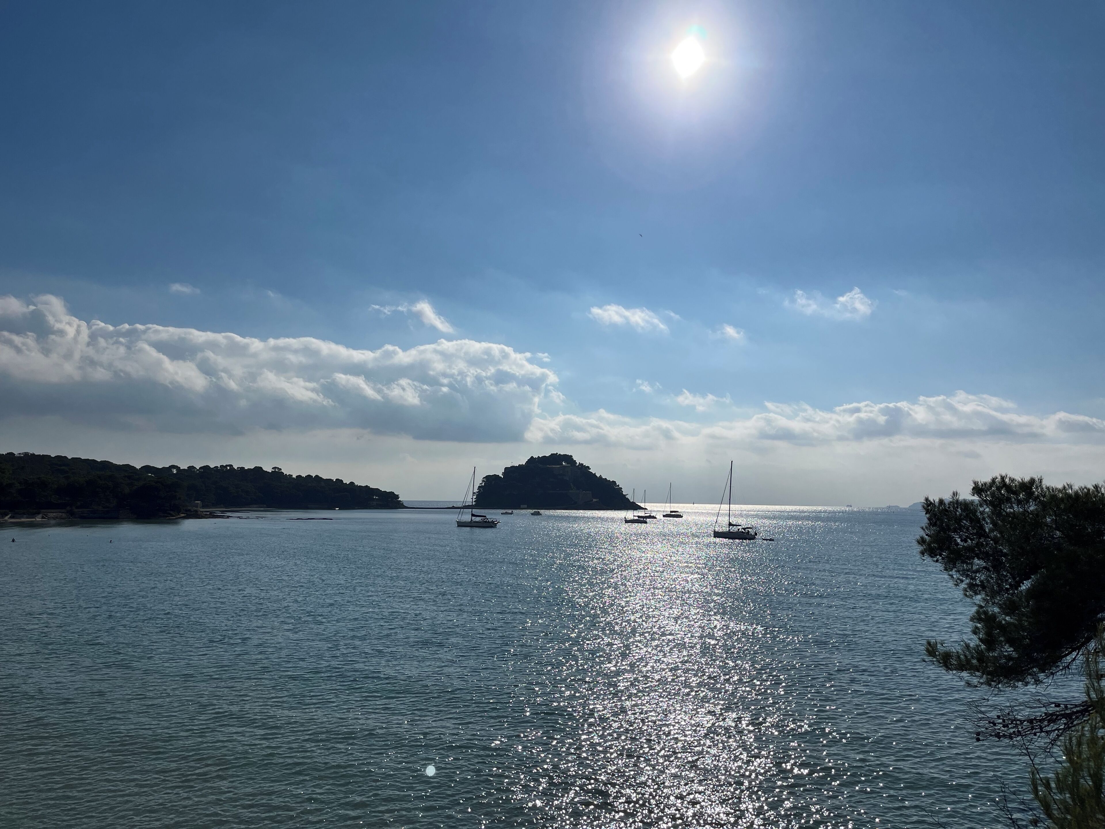A calm sea with boats and a clear sky.