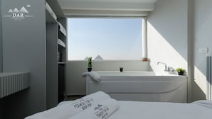 A modern bathroom with a bathtub, a window, and a towel with text. - Dar Pyramids View Inn RoofTop (Giza)
