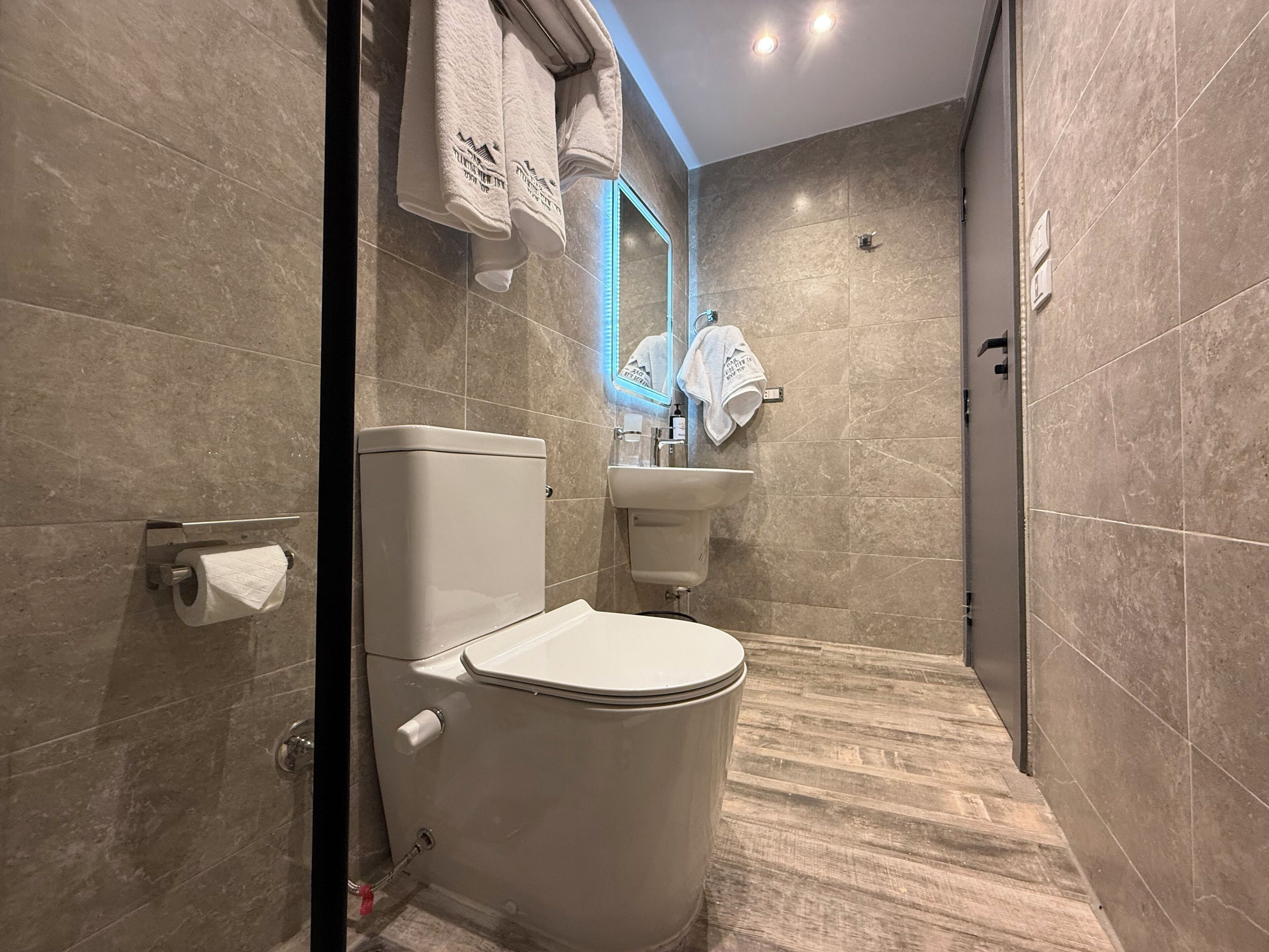 Un baño moderno con inodoro, lavamanos y espejo.