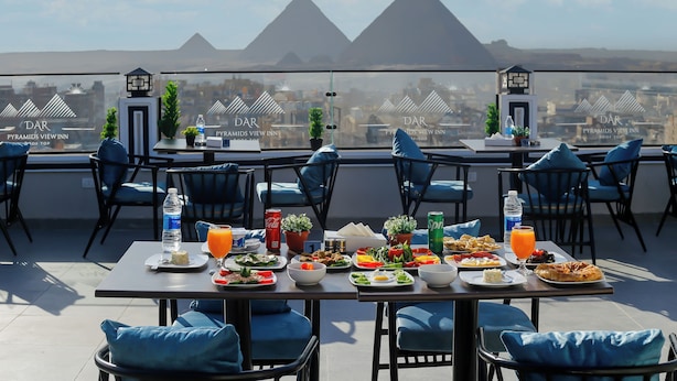 A rooftop dining area with tables set for breakfast, overlooking the pyramids. - Dar Pyramids View Inn RoofTop (Giza)