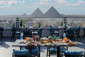 A rooftop dining area with tables set for breakfast, overlooking the pyramids. - Dar Pyramids View Inn RoofTop (Giza)