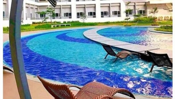 Ein Schwimmbecken mit geschwungenem Design, umgeben von einem modernen Gebäude mit Balkonen.