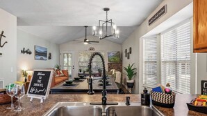 A kitchen with a double sink, a chandelier, and a sign that reads "Welcome to the Smokies, Life is good!"