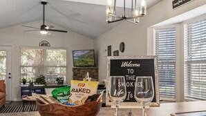 A cozy kitchen with a sign reading "Welcome to the Smokies," a bowl of snacks, and two glasses on a counter.