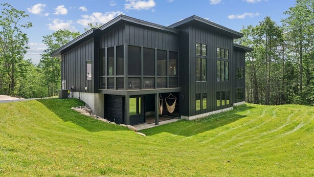 A modern two-story house with large windows and a covered outdoor area.
