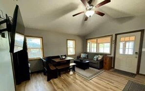 A spacious living room with a ceiling fan, a sofa, a coffee table, and a television.