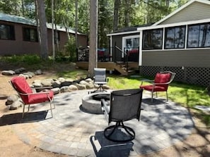 Eine Terrasse mit Gartenmöbeln, einem Feuerkorb und einem Gebäude mit einer Holzterrasse.