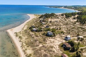 An aerial view of a coastal area with houses, a beach, and a clear blue sea.