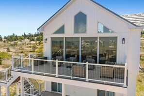 A modern house with a balcony, large windows, and a deck.