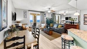 A spacious living area with a dining table, sofas, and a kitchen island.
