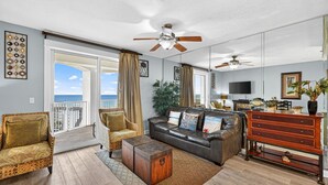 A living room with a sofa, armchairs, a coffee table, a TV, and a dresser.