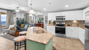 A modern kitchen with white cabinets, a granite countertop, and stainless steel appliances.