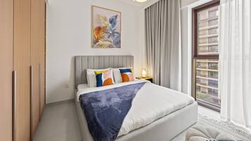 Une chambre à coucher moderne avec un lit, une table de chevet, une fenêtre avec des rideaux et un tableau au mur.
