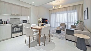 Un appartamento moderno con cucina, zona pranzo e soggiorno. Dispone di un tavolo da pranzo con sedie, un divano, un tavolino e una TV.