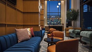 Una zona lounge moderna con un divano blu, poltrone arancioni e un bar fornito di numerosi alcolici.