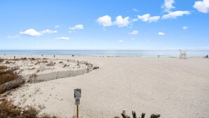 A wide sandy beach with a wooden fence and a lifeguard tower.