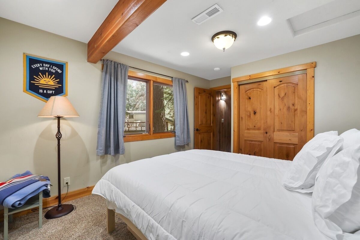 Un dormitorio con cama, lámpara de pie, ventana con cortinas y puerta.