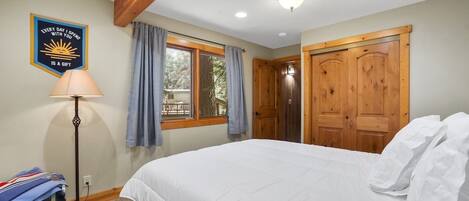 Un dormitorio con cama, lámpara de pie, ventana con cortinas y puerta.