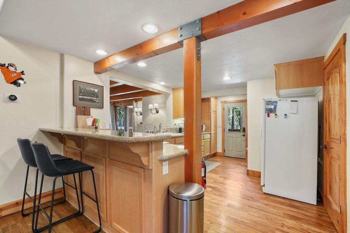 A kitchen with wooden cabinets, a white refrigerator, and a bar stool.