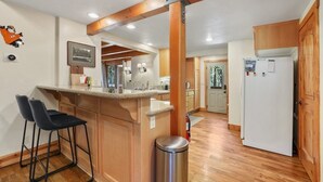 A kitchen with wooden cabinets, a white refrigerator, and a bar stool.