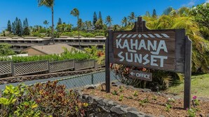 Un letrero de madera con la inscripción "KAHANA SUNSET" y "OFICINA", señalando una ubicación.