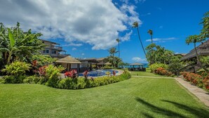 Un resort bien cuidado con piscina, abundante vegetación y un cielo azul despejado.
