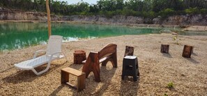 A beach with a wooden bench, a white chair, and a small table.