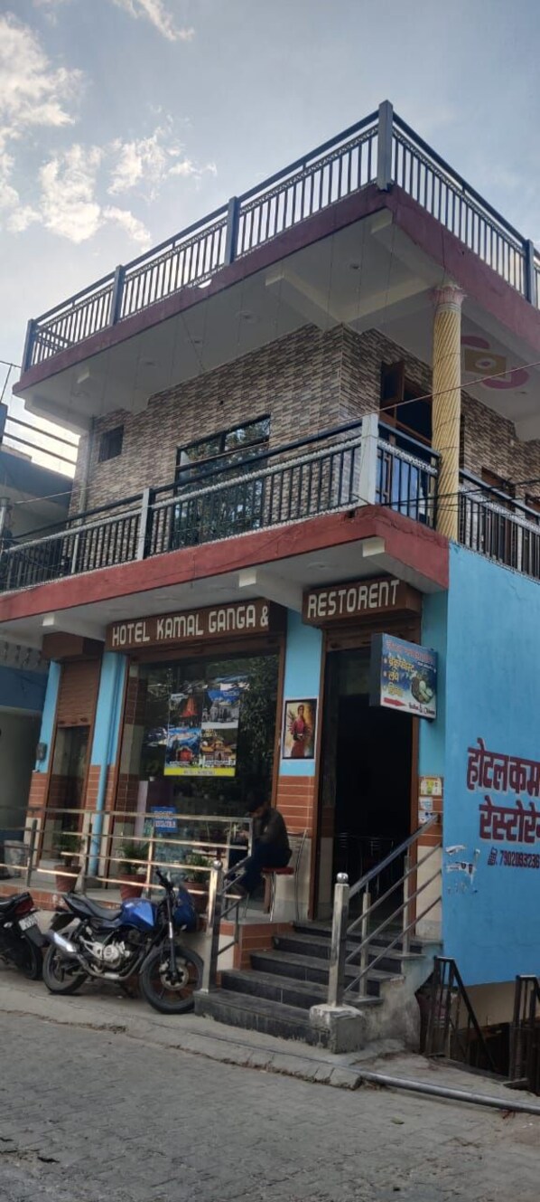Un edificio de dos pisos con un letrero que dice "Hotel Kamal Ganga & Restaurant" en la planta baja.