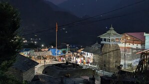 A nighttime view of a mountainous area with a small settlement, including a stone structure and a few buildings with colorful roofs. - Hotel Kamal Ganga & Restaurant (Rajgarhi)