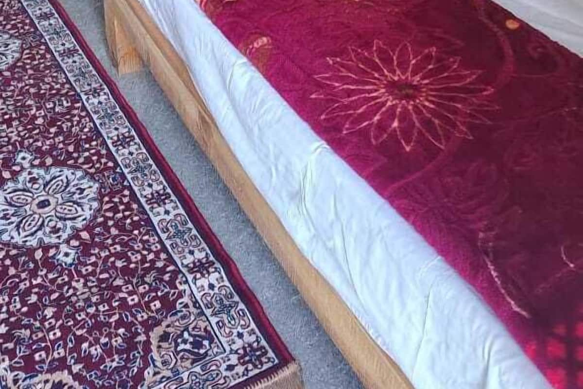 A room with two single beds, a patterned rug, and a curtain.