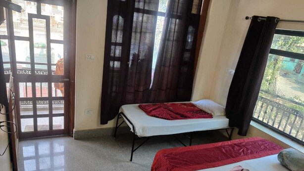 A room with two beds, a balcony, and a view of the outside. - Hotel Kamal Ganga & Restaurant (Rajgarhi)