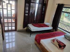Una habitación con dos camas, un balcón y vistas al exterior.