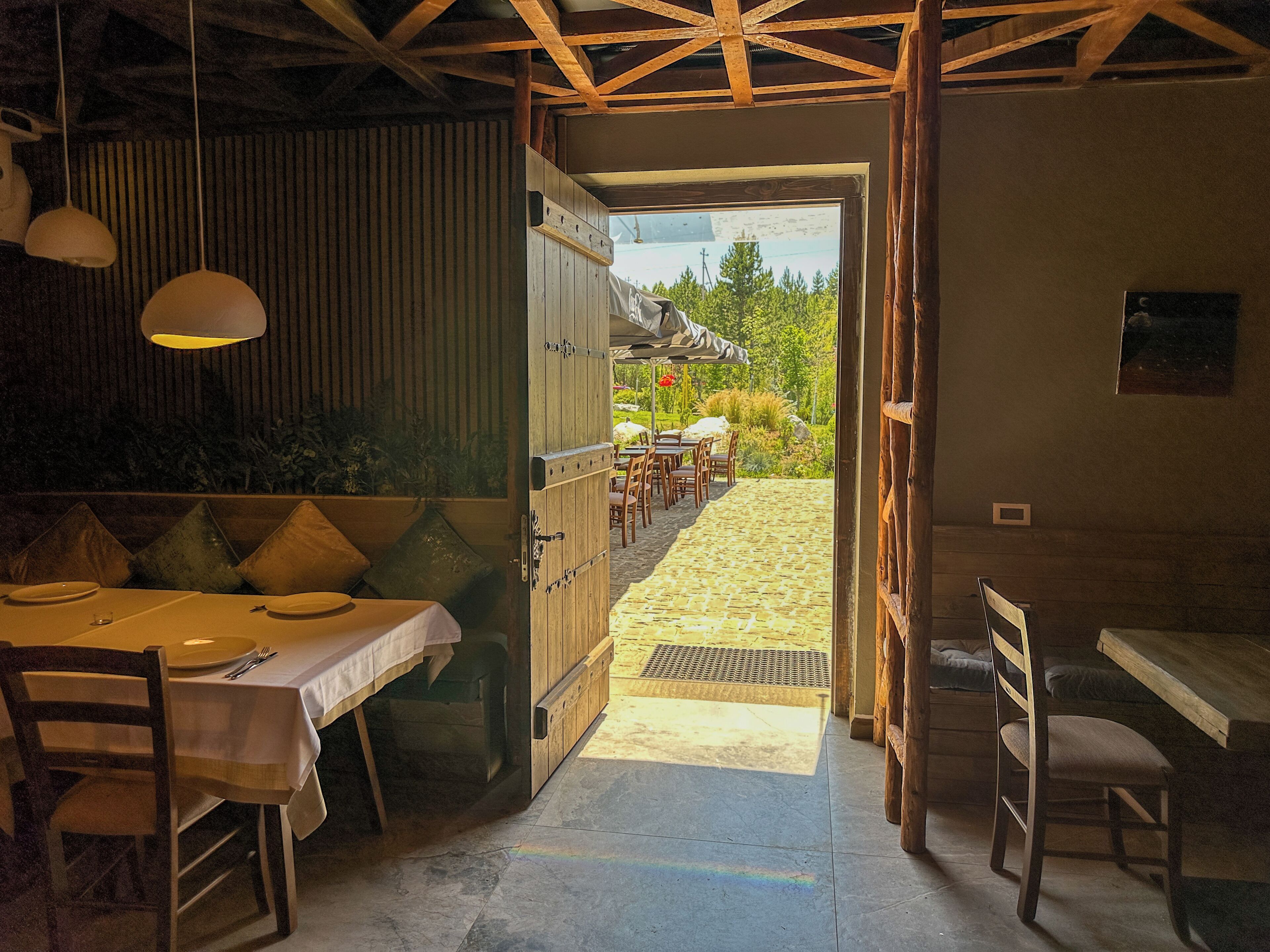 An open-plan dining area with a view of a garden and outdoor seating.