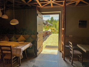 Un espace repas à aire ouverte donnant sur un jardin et comprenant un coin salon extérieur.