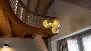 Un escalier en bois surmonté d’un luminaire moderne.