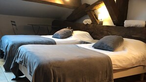 A room with two beds, wooden beams, a window, and a lamp. - TIME GOLD (Ars-sur-Formans)