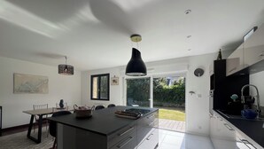 Una cocina moderna con una isla central, armarios blancos y un comedor con sillas y una mesa.