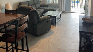 A living room with a sofa, a dining table, and a ceiling fan. - Beach view w/ large balcony 200' from sand. Heated pool, hot tub, 4 beds, 2 bath (South Padre Island)