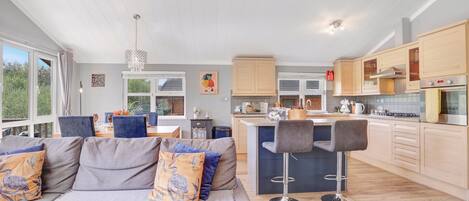 A modern kitchen with wooden cabinets, a central island, and a bar stool.