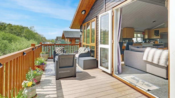 A deck with outdoor furniture, a sliding glass door leading to a living area, and a view of the surrounding landscape. - Fairway View - North East Escapes (Swarland)