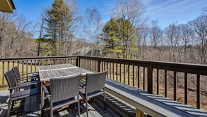 A wooden deck with a table and chairs, overlooking a forested area. - Game Room Condo, Sugar Hill, Pet-Friendly (Quechee)