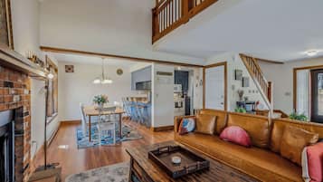A spacious living room with a fireplace, a wooden coffee table, a leather sofa, and a dining area with a table and chairs.