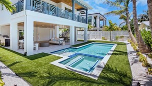 A modern two-story house with a swimming pool, outdoor seating, and a fenced yard.