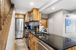 Una cocina moderna con electrodomésticos de acero inoxidable, armarios de madera y una encimera de granito negro.