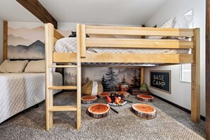 A bunk bed with a ladder, a bed with a quilted cover, a wall with a forest mural, and a sign that reads 'BASE CAMP'. - Updated townhome - Walk to Holiday Valley (Ellicottville)